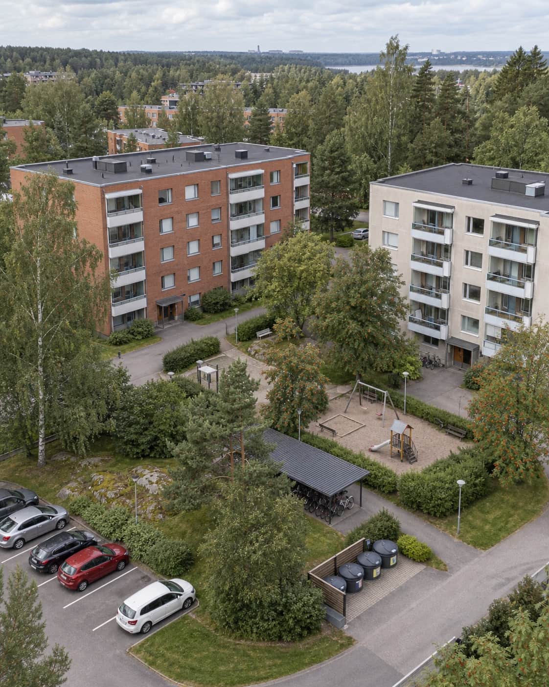 Suomalainen kerrostalopiha, leikkialue ja pyöräkatos ylhäältä kuvattuna
