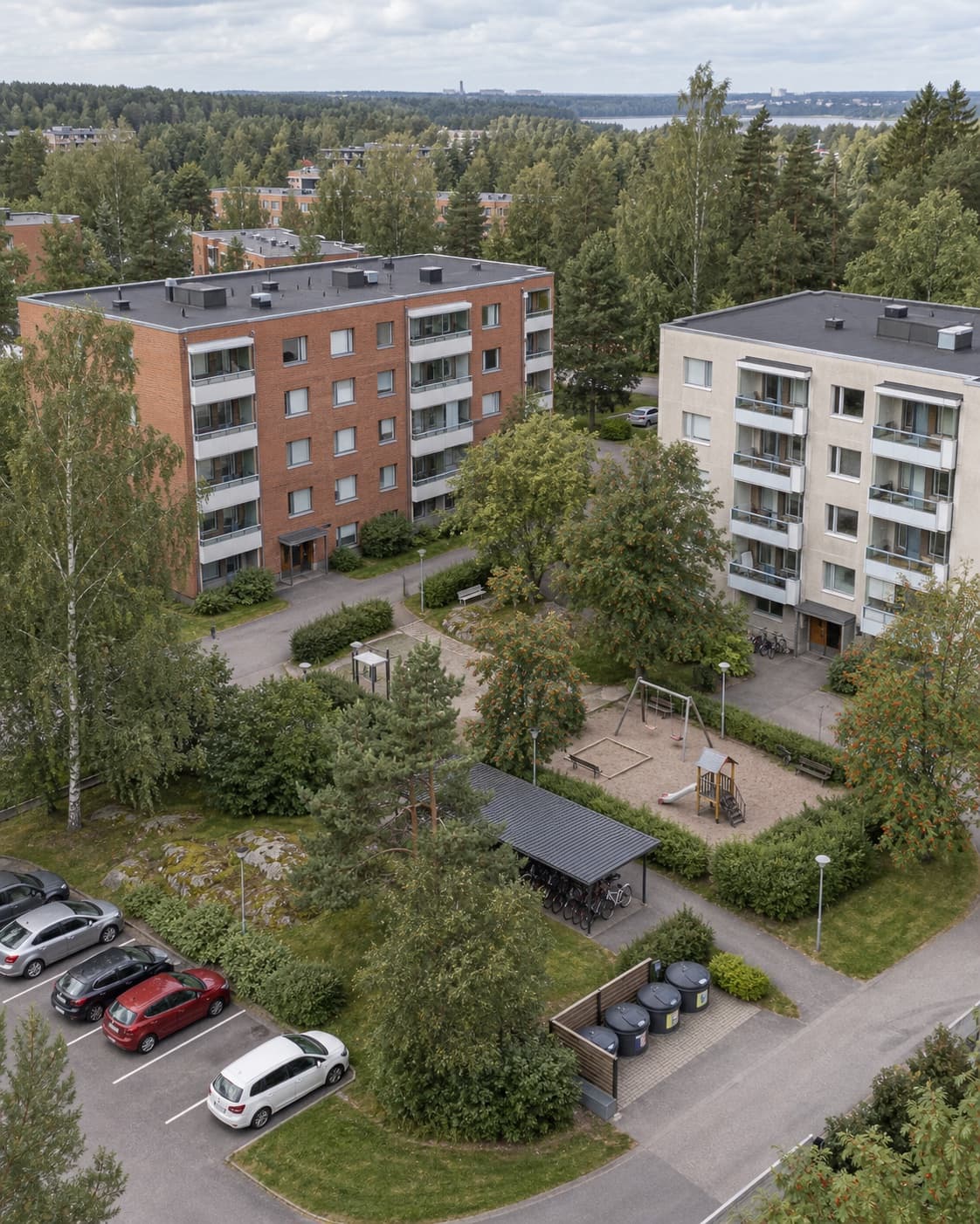 Suomalainen kerrostalopiha, leikkialue ja pyöräkatos ylhäältä kuvattuna